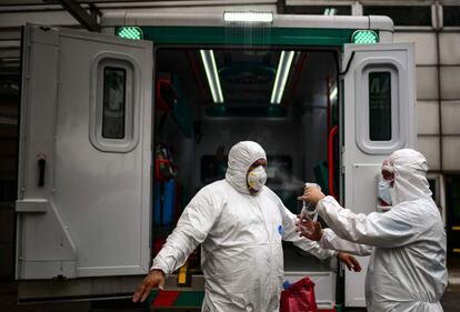 Un sanitario desinfecta a otro después de trasladar a un paciente con síntomas de covid-19, en Buenos Aires (Argentina).