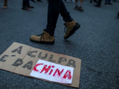 Manifestante bolsonarista caminha sobre cartaz durante protesto em frente ao consulado chinês no Rio de Janeiro contra uma suposta conspiração do país asiático para espalhar a covid-19 pelo mundo