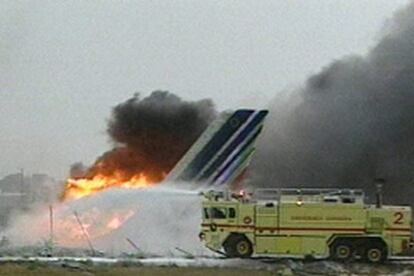 Imagen de televisión del avión incendiado mientras un camión de bomberos lucha contra las llamas.