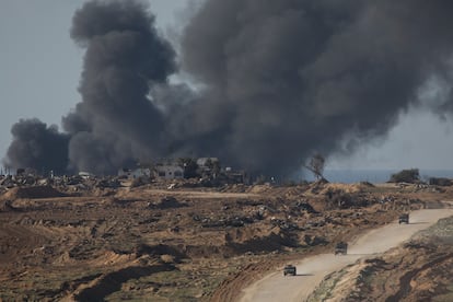 Vehículos israelíes se retiran de la franja de Gaza mientras el humo de los bombardeos sobre el enclave se ve a lo lejos.