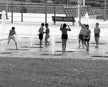 Un grupo de niños juega con el agua en el parque Juan Carlos I de Madrid.