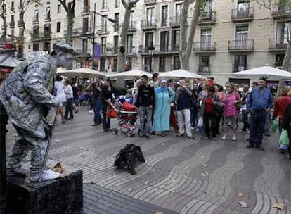 Un grupo de turistas formando un semicírculo alrededor de una estatua en La Rambla.