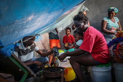 Enoc Jean Batis (izquierda), de 28 años, y su esposa, Celimaine Heixil, de 29, con su hija en brazos, cocinaban en el campamento improvisado instalado en la escuela Darius Denis, en Puerto Príncipe, el 5 de mayo. 