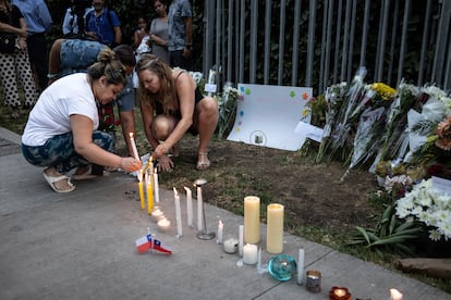 Mujeres encienden velas afuera  de la casa de Sebastián Piñera en Santiago, este martes.