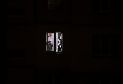 Una mujer retira cinta adhesiva colocada en una ventana de su piso, iluminado por generadores, ayer en Kiev.