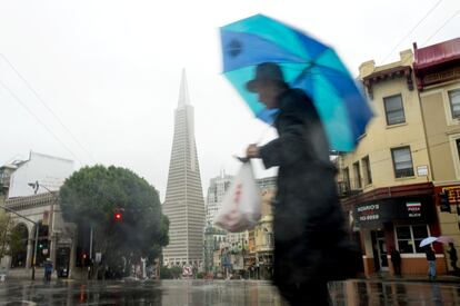 Un hombre camina por las calles de San Francisco en donde la policía ha cerrado varios carriles en las autopistas del Estado debido a las inundaciones y árboles caídos.