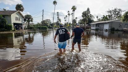 Thomas Chaves y Vinny Almeida caminan a través de las inundaciones provocadas por el huracán Helene en el vecindario de Shore Acres en St. Petersburg, Florida. El viernes 27 de septiembre de 2024. 