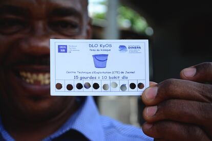 Frantz Pierre-Louis, director de la agencia municipal de agua de Jacmel, muestra una tarjeta de pago de agua en un kiosco. 15 gurdas son unos 20 céntimos de euro y 10 'bokits', unos 200 litros.