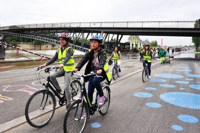 Unas jóvenes pasean en bicicleta en una carretera junto al Sena.