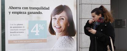 Una  mujer pasea delante de una publicidad de ahorro de un banco. 