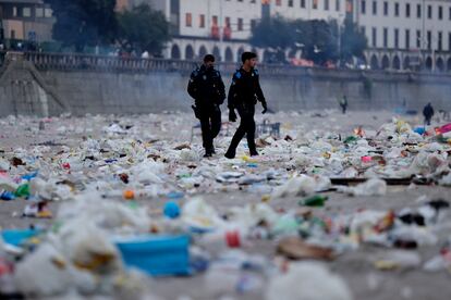 Dos agentes caminan entre los restos de basura tras la celebración de la noche de San Juan en la playa de A Coruña, este viernes. 