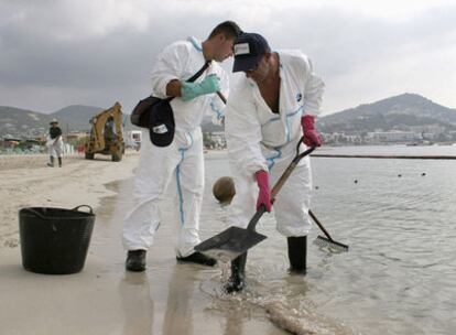 Operarios de limpieza retiran restos del vertido de fuel en la playa ibicenca de Talamanca.