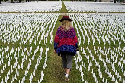 A artista Suzanne Brennan Firstenberg caminha entre milhares de bandeiras brancas instaladas em memória dos americanos que morreram da pandemia em 27 de outubro em Washington.