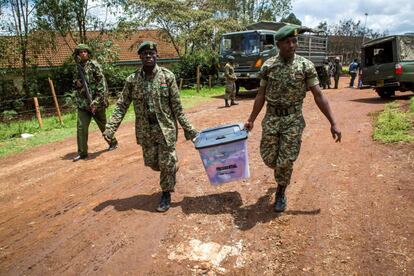 Dos oficiales de la policía keniata portan una urna para que los residentes puedan ejercer su derecho a voto en un colegio de educación primaria en Nairobi.