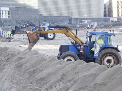 Varios operarios trabajan en la playa de la Zurriola, en San Sebastián, destrozada tras el temporal del domingo.