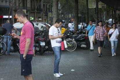 Dos homes parats al mig del carrer consulten el telèfon.