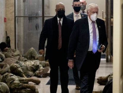 Miembros de la Cámara de los Representantes caminan entre los militares que descansan en los pasillos, este miércoles en Washington.