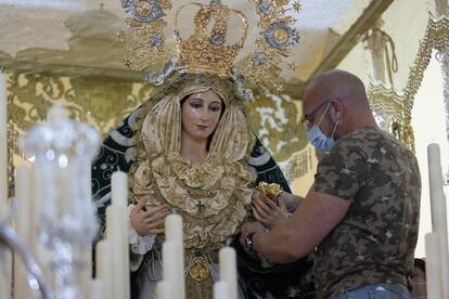 El vestidor de la Real Cofradía de Nuestro Padre Jesús a su Entrada en Jerusalén y María Santísima del Amparo, David Anaya, coloca a la virgen la flor en la mano antes de su procesión el Domingo de Ramos.