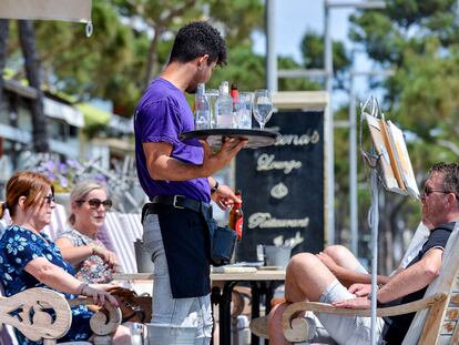 Un camarero atiende a unos clientes de una mesa, en la terraza de un restaurante del paseo marítimo de Platja d'Aro (Girona).