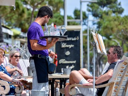 Un camarero sirve a unos clientes de una mesa de un restaurante del Paseo Marítimo de Platja d'Aro, en Girona.