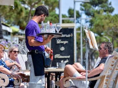 Un camarero atiende a unos clientes de una mesa, en la terraza de un restaurante del Paseo Marítimo de Platja d'Aro (Girona).