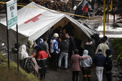 Familiares de los mineros atrapados esperan información alrededor de una carpa de la Cruz Roja.