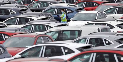 Una trabajadora de Ford camina entre automóviles aparcados en el exterior de la planta en Almussafes (Valencia).