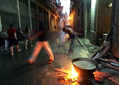 Transeúntes pasan junto a una olla de <i>caldosa,</i> un guiso típico cubano, en una calle de la Habana Vieja.