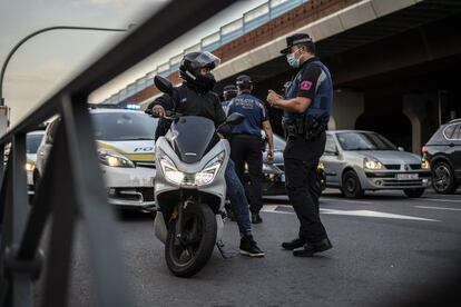 Durante al menos 14 días, a partir de este lunes, y en todo el territorio de la Comunidad de Madrid quedan prohibidas las reuniones, privadas o en la calle, de más de seis personas salvo los convivientes y el ámbito laboral o institucional. El resto de nuevas restricciones afecta a 37 zonas básicas de salud de seis distritos de la capital y otros siete municipios. Las entradas y salidas de estas zonas quedan restringidas salvo para acudir a trabajar y otras actividades o trámites imprescindibles. En la imagen, un agente de policía controla el flujo de vehículos a la entrada de Puente de Vallecas.