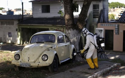 Un trabajador fumiga un coche, ayer en Brasil.