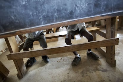 Las piernas de los escolares se ven debajo de una pizarra que se utiliza para dividir a los estudiantes de los diferentes niveles en una de las aulas de primaria en la Escuela Evangélica de Bethesda, en Canaán, Haití . La vida aquí no es fácil y el mayor temor es que Canaán se convierta en otro Cité Soleil, un laberinto de chozas originalmente planificadas como una comunidad para los trabajadores pero que acabó como gheto pandillero.