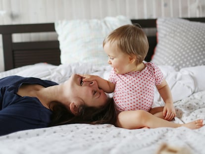 Una madre juega con su hijo en la cama.