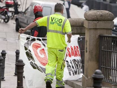 Operarios del ayuntamiento, escoltados por la Ertzaintza, retiran carteles de apoyo a ETA en las calles de Vitoria