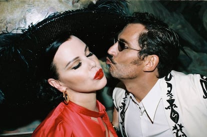 La protagonista de 'Arde Madrid', Debi Mazar, recibe el beso del director de la serie, Paco León. Ella lleva pendientes Aristocrazy, vestido Self-Portrait para Mytheresa y tocado Betto García. Él viste camisa y chaqueta Dries Van Noten y sello Bárcena.