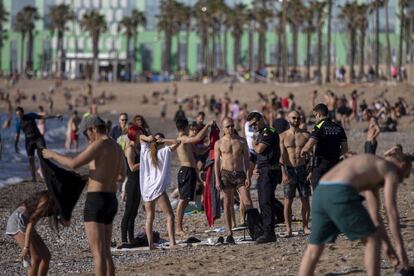 Agentes de la policía piden a los ciudadanos no tumbarse en la playa, en Barcelona.