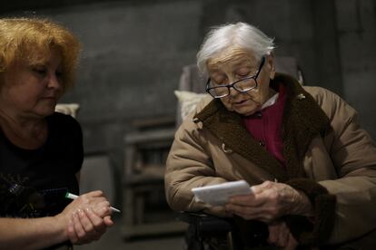 Maria leía junto a su hija Natalya, de 58, en el interior del sótano en el que viven, el 26 de julio. María sufre problemas de movilidad, pérdida progresiva de la memoria y confusión, que han empeorado desde el ataque al piso en el que vivía.