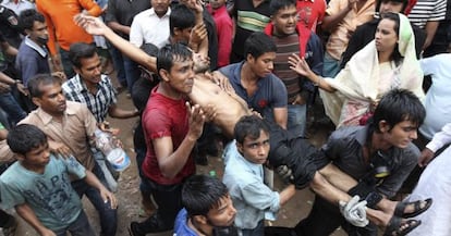 Un grupo de personas carga con un herido en el incendio de una fábrica textil en las cercanías de Daca, Bangladesh.