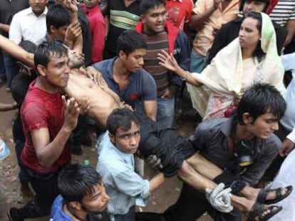 Un grupo de personas carga con un herido en el incendio de una f&aacute;brica textil en las cercan&iacute;as de Daca, Bangladesh. 