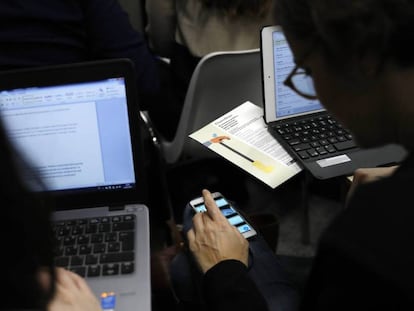 Duas pessoas trabalham com seus computadores e celulares, em uma imagem de arquivo.