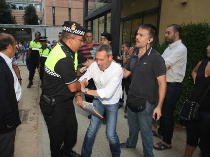 Un policía local forcejea con el líder de PxC, Josep Anglada, a las puertas del Ayuntamiento de Salt durante el pleno de ayer.