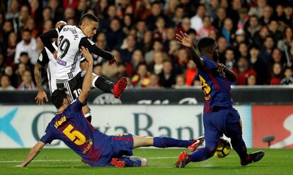 El jugador del Valencia Rodrigo Moreno dispara el balón ante los jugadores del FC Barcelona Sergio Busquets y el francés Samuel Umtiti.