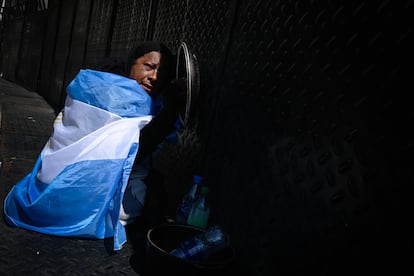 Una mujer en silla de ruedas golpea con la tapa de una olla el vallado alrededor del Congreso.