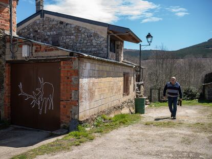 Un vecino de Linarejos pasa junto a una puerta pintada con la silueta del ciervo Carlitos.