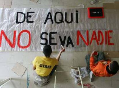 Unos niños pintan el lema de resistencia de la parroquia de San Carlos Borromeo, <i>De aquí no se va nadie,</i> extraído de un poema de León Felipe.