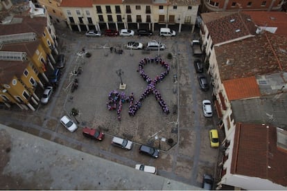 Niños y mujeres de varias asociaciones de Mondéjar forman un lazo violeta en la Plaza Mayor del pueblo con motivo del Día de la Mujer (vista desde el campanario de la iglesia).