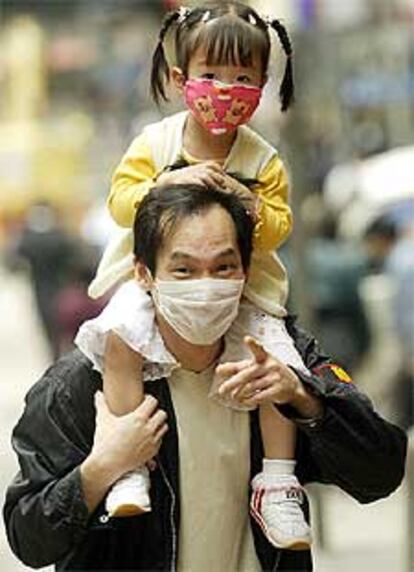 Un padre y su hija en Hong Kong llevan mascarillas contra la neumonía.