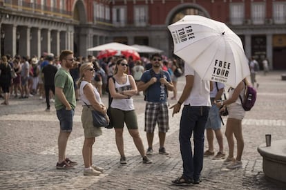 Un grupo de turistas escucha a un guía de un free tour en la plaza Mayor.