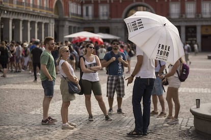 Un grupo de turistas escucha a un guía de un free tour en la plaza Mayor.  