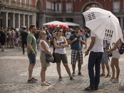 Un grupo de turistas escucha a un guía de un free tour en la plaza Mayor.  