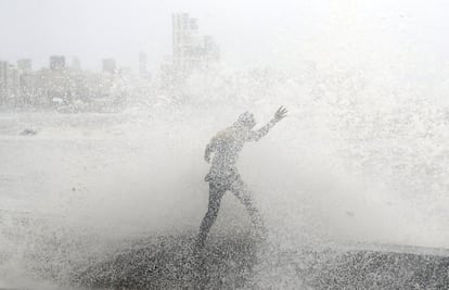 Un hombre pierde el equilibrio tras ser alcanzado por una ola en la costa de Bombay (India).